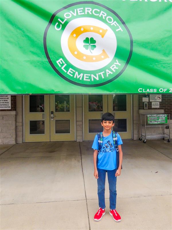 boy smiling under Welcome to Clovercroft sign